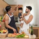 same sex parenting with two fathers caring for their baby in the kitchen