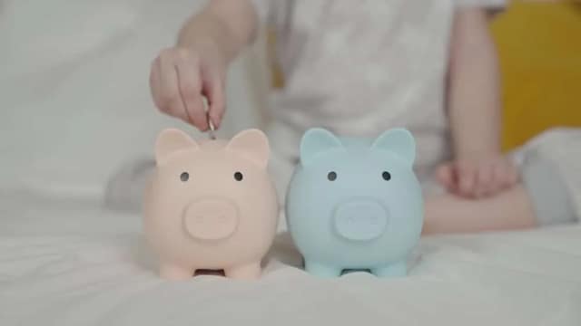 Child putting coins into piggy banks illustrating the cost of raising a child