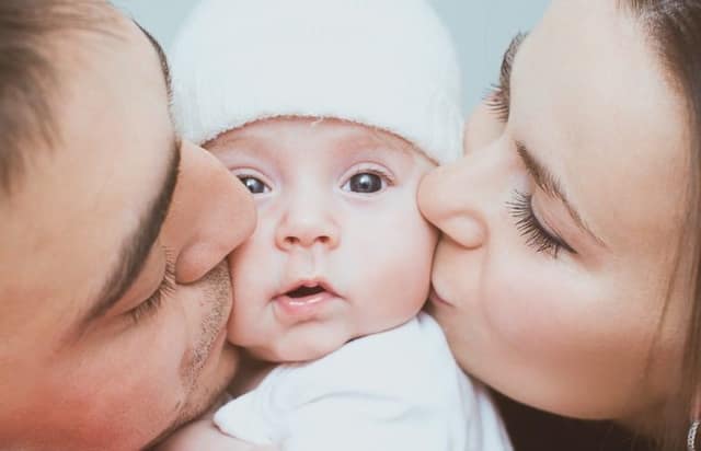 co parenting family with mother father and newborn baby together at home