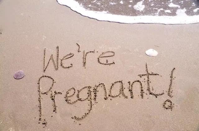 Pregnancy announcement written in sand on beach with message “We are pregnant”