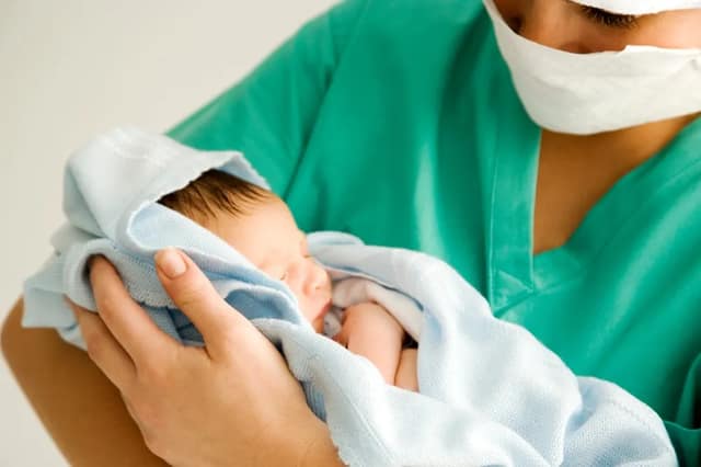 Nurse holding a newborn baby born through mitochondrial donation