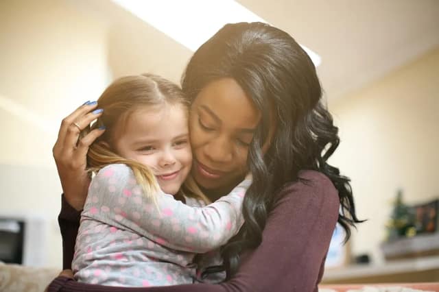 Adopt a child concept showing a woman hugging a young girl in a warm and affectionate moment