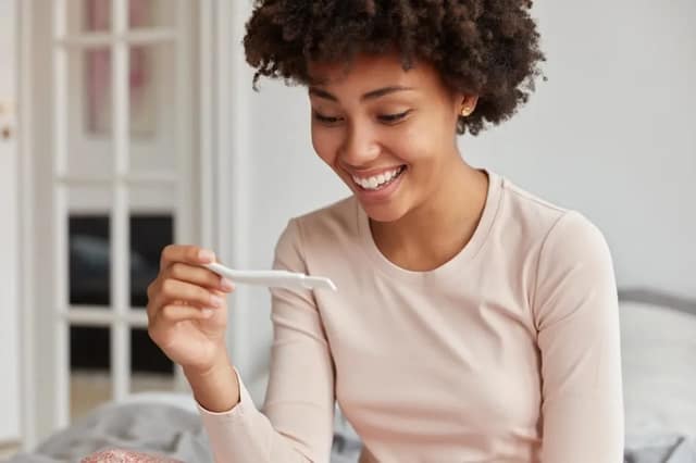 Happy woman holding a positive test pregnancy after miscarriage