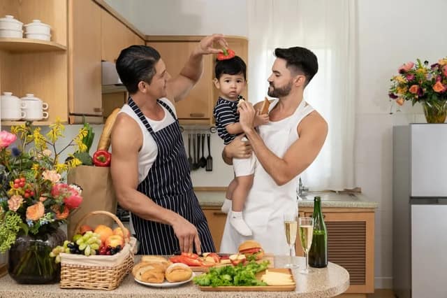 same sex parenting with two fathers caring for their baby in the kitchen