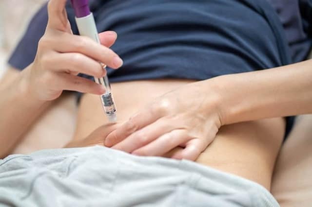 A woman injects hormones using a syringe pen to increase ovarian stimulation
