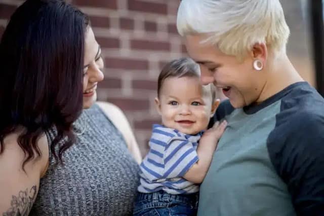 ready for a baby lesbian couple holding their baby at home in a warm family moment