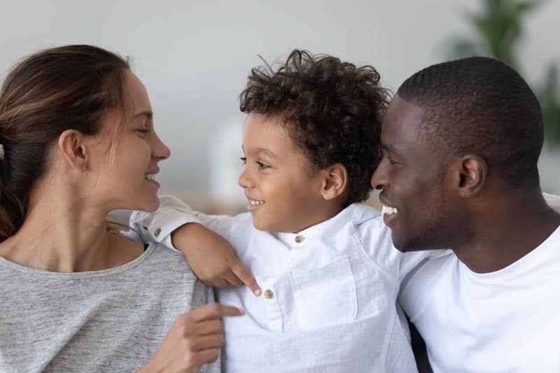 smiling young multiethnic parents hug cuddle