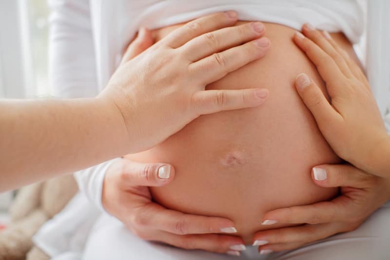surrogacy laws several hands touching pregnant woman belly