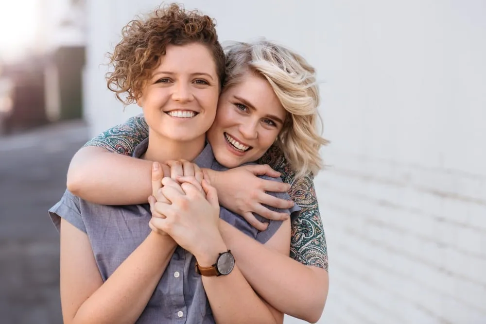 Portrait of smiling young lesbian couple hugging outdoors considering home insemination lesbian couples fertility options together