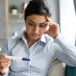 at home insemination with woman holding pregnancy test looking concerned