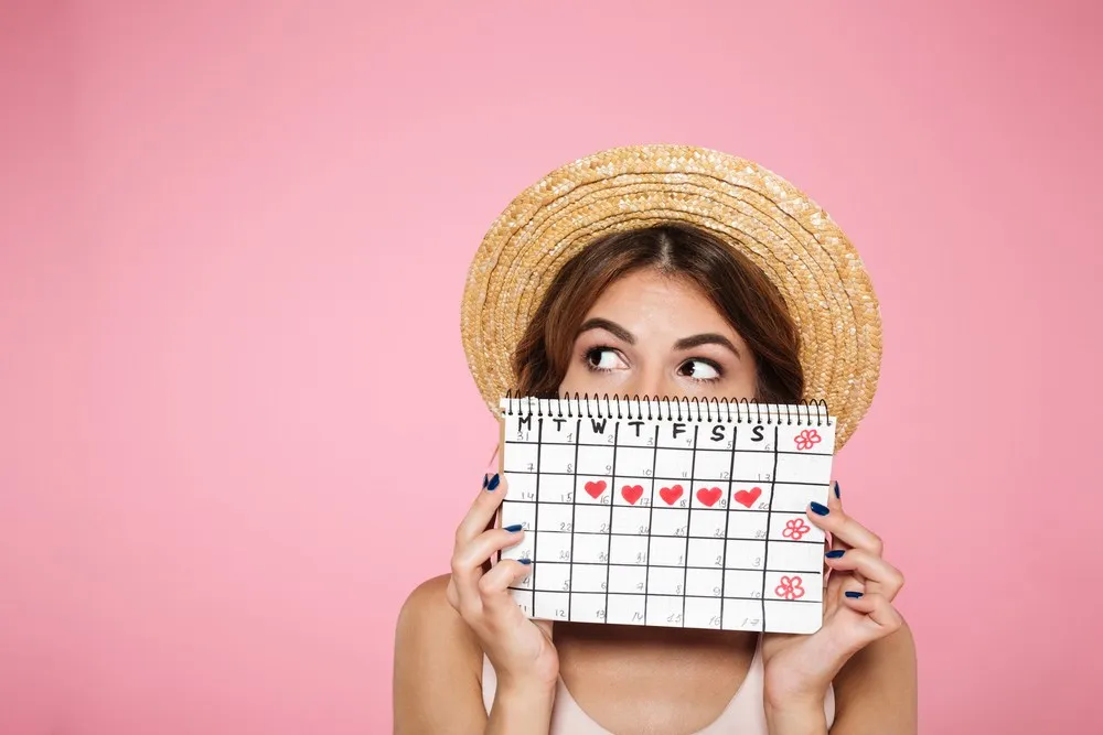 Woman holding a menstrual calendar and wondering if she can get pregnant on period